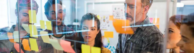 Team collaborating over sticky notes on a glass board, showcasing Exigo Tech's Project Services with Agile Methodology delivery model in Australia for efficient and on-time project completion Team collaborating over sticky notes on a glass board, showcasing Exigo Tech's Project Services with Agile Methodology delivery model in Australia for efficient and on-time project completion